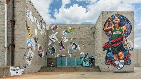 large mural depicting little girl blowing bubbles surrounded by books