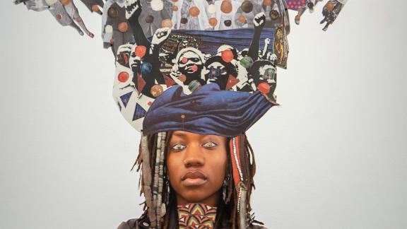 head of woman standing in front of a mixed-media collage depicting many raised fists