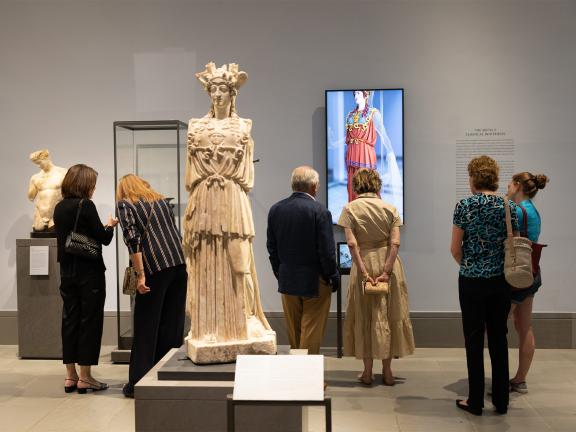 A group of patrons viewing sculptures around the Statue of Athena and its digital color rendering