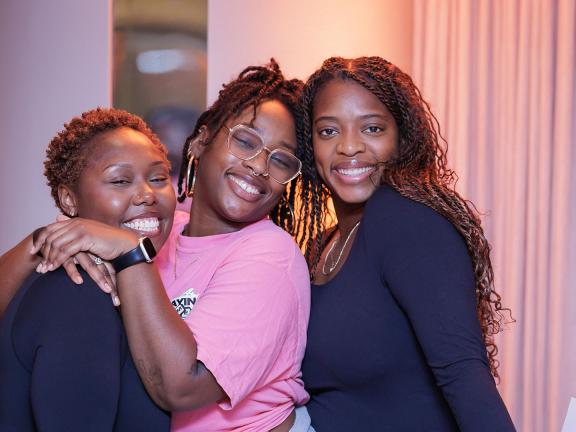Three Museum visitors smiling and posing for photo; two on left in embrace