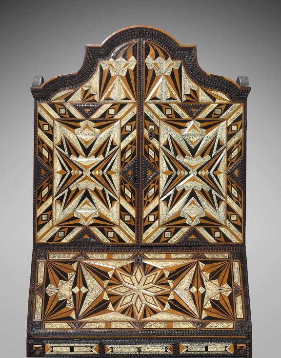 An elaborately decorated desk and bookcase with arabesque wooden inlays.