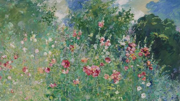 A colorful patch of flowers and trees before a deep blue sky.