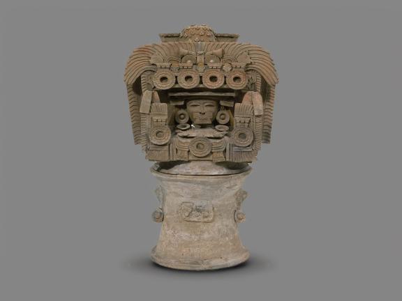 Tiquisate Teotihuacan-style incense burner top rendering a human head wearing wide, circular earflares and a large headdress that forms a building which surrounds the figure