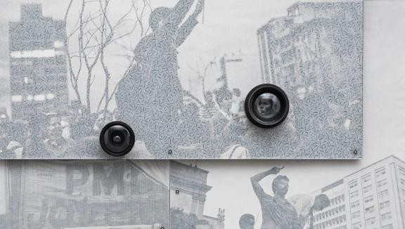 A close-up of a grayscale photograph with old camera lenses mounted on top of it.