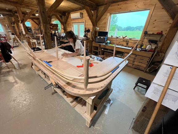 A person constructs a wooden bench in a workshop.