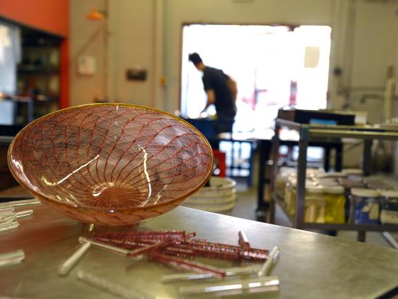 Glass bowl in glass studio with figure in background