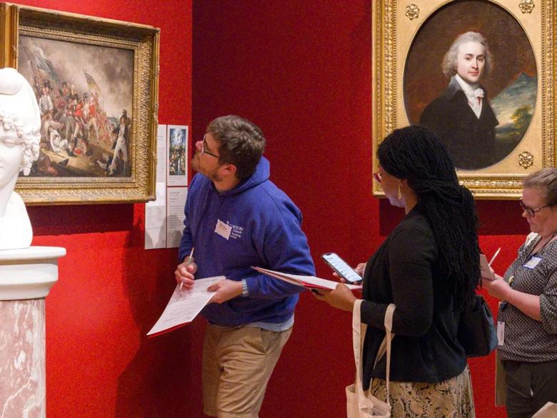 Educators look closely at an oil painting depicting the Battle of Bunker's Hill 