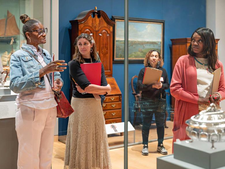 A small group of teachers holding clipboards discuss an artwork in the galleries