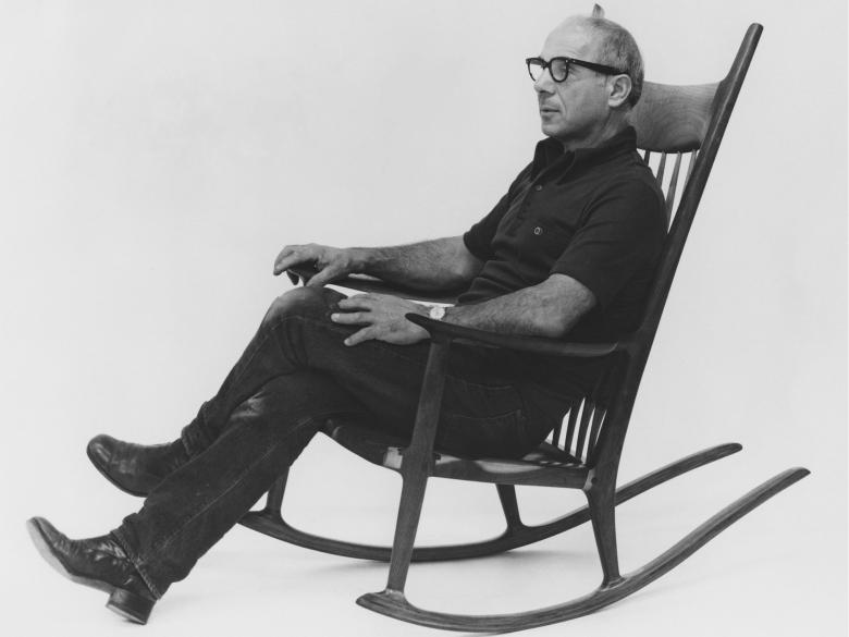 A man sits with his legs crossed in a rocking chair.