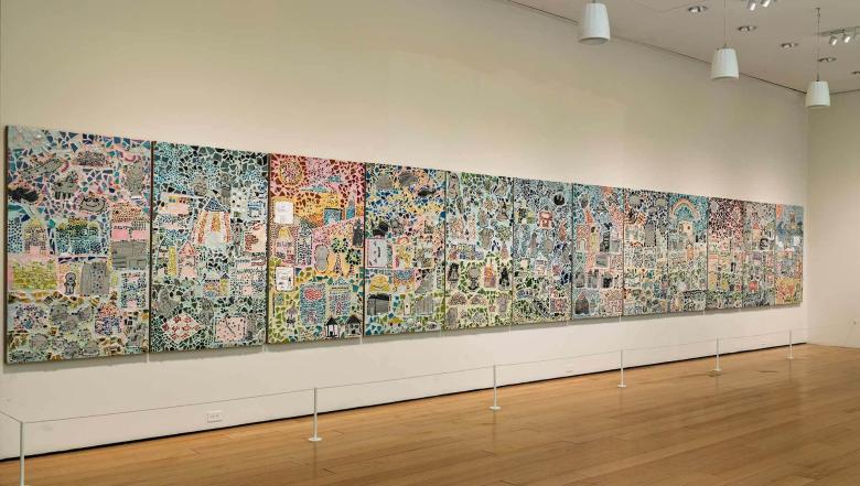 A colorful mosaic on a white wall above a hardwood floor.