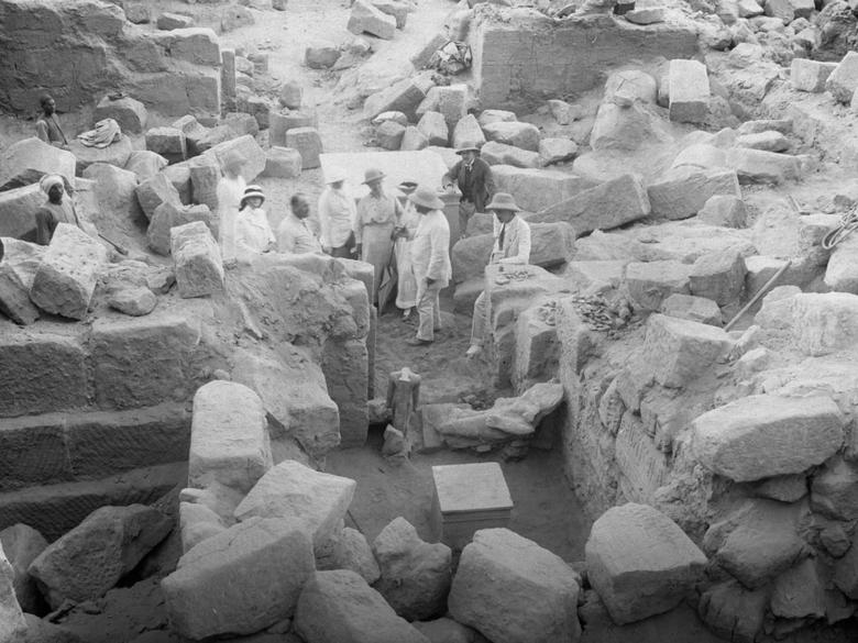 Black-and-white photo of men standing around ancient ruins.