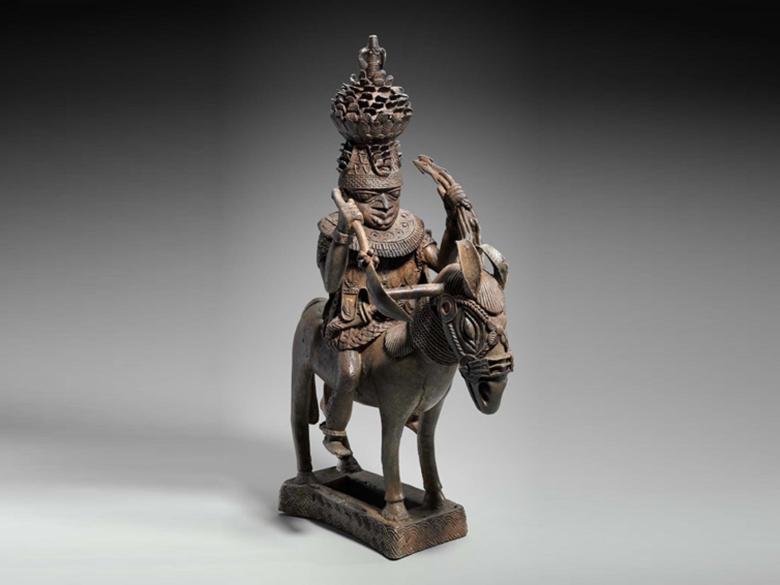 Copper sculpture of mounted man with a crown and holding the reins of a horse